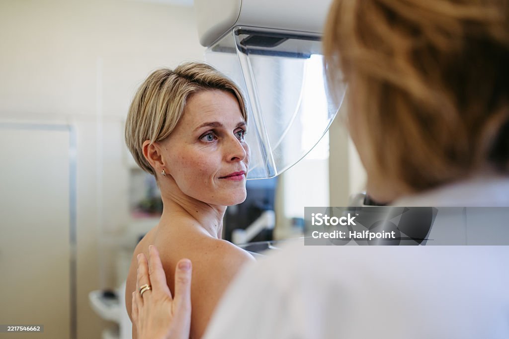 Medical professional calming patient ahead of mammogram procedure. Preventive breast cancer screening.